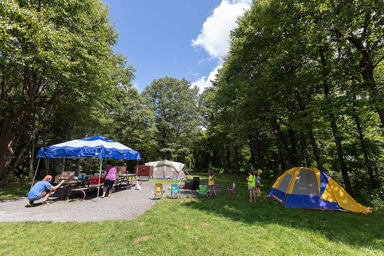 Family setting up a campsite under a canopy at Big Meadows Campground